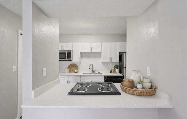A kitchen with white cabinets and a black stove top.