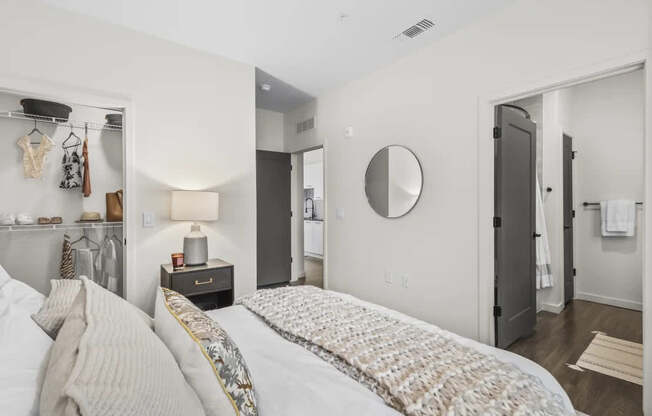 A bedroom with a bed, a mirror, and a lamp.
