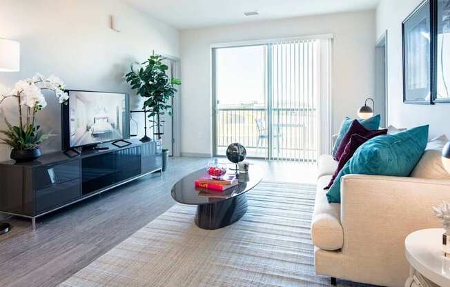 A modern living room with a large couch, a coffee table, and a flat-screen TV.