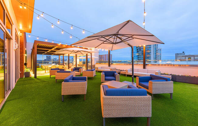 a lounge area with chairs and umbrellas on the rooftop of a building