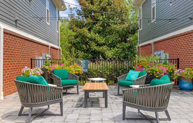 a patio with chairs and a table in front of a brick building