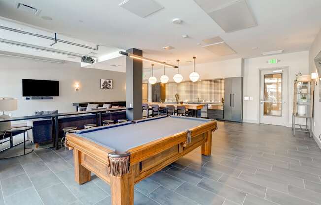 a pool table in the resident lounge with a bar and television in the background