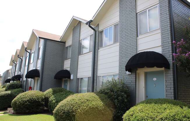 apartments painted white and grey with teal doors and black awnings and mature landscaping  at Huntsville Landing Apartments, Alabama, 35806