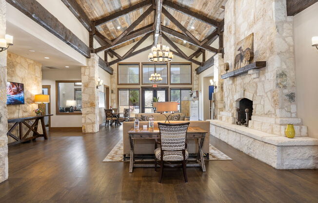 a dining room with a table and chairs in front of a stone fireplace at Lakeline East Apartments, Cedar Park