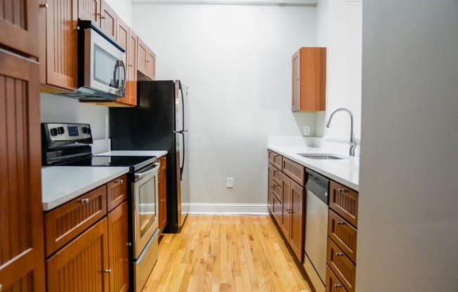 a kitchen with wood floors and wooden cabinets and a black refrigerator at East 4th Street, Cleveland, Ohio