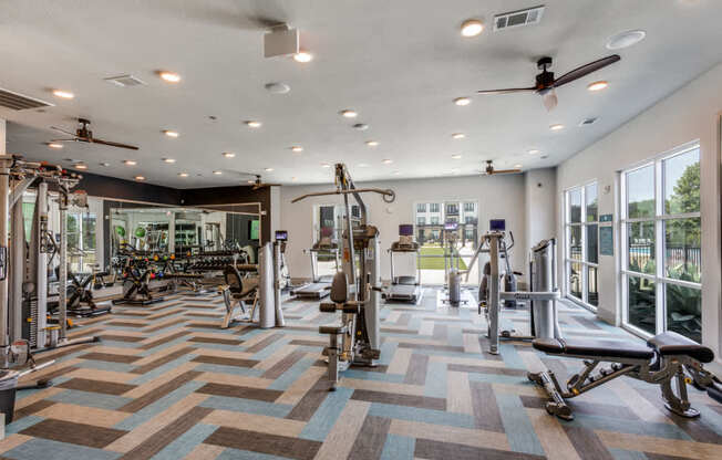 A gym with a variety of equipment including treadmills, weights, and exercise machines.