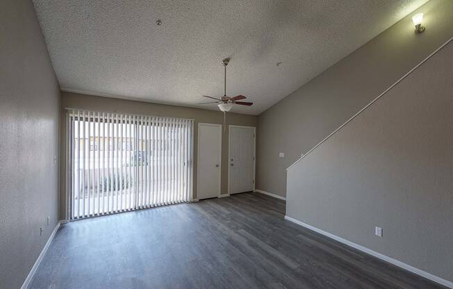 an empty living room with a ceiling fan and sliding glass doors