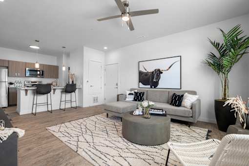 A modern living room with a grey couch, a coffee table, and a painting of a bull on the wall.