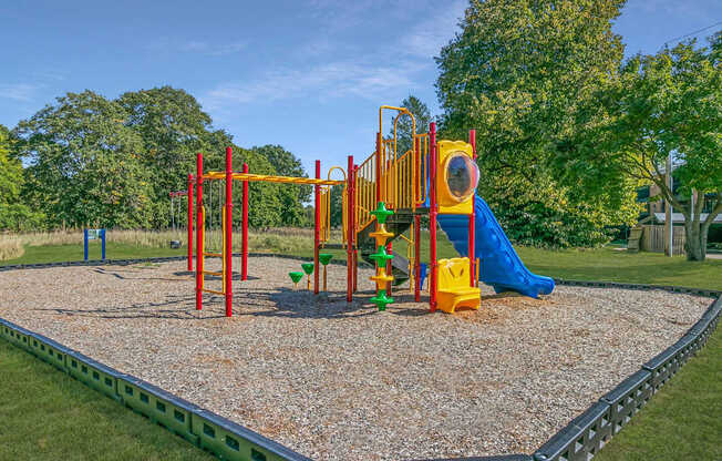 A playground with a yellow slide and a green slide.
