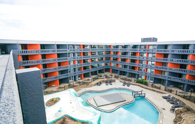 A large swimming pool in the middle of a courtyard surrounded by orange and grey buildings.