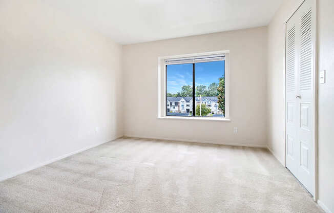 A bedroom with a carpeted floor and a window at Arbor Lakes Apartments in Elkhart, IN