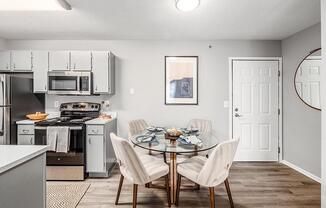 A modern kitchen with a glass dining table set for four.