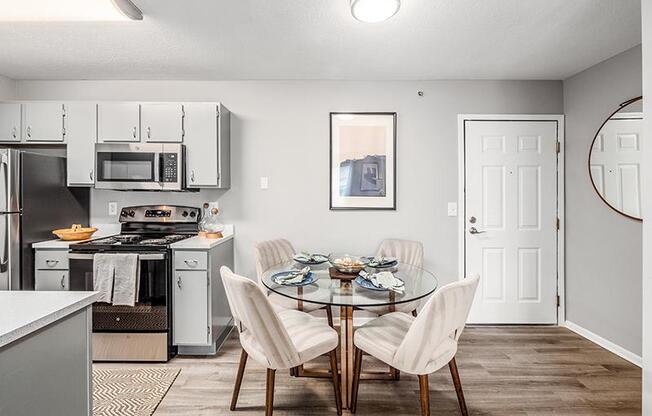 A modern kitchen with a glass dining table set for four.