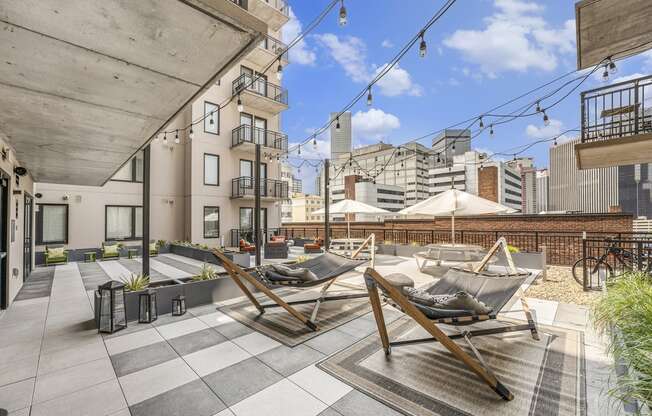 a rooftop terrace with lounge chairs and a city in the background