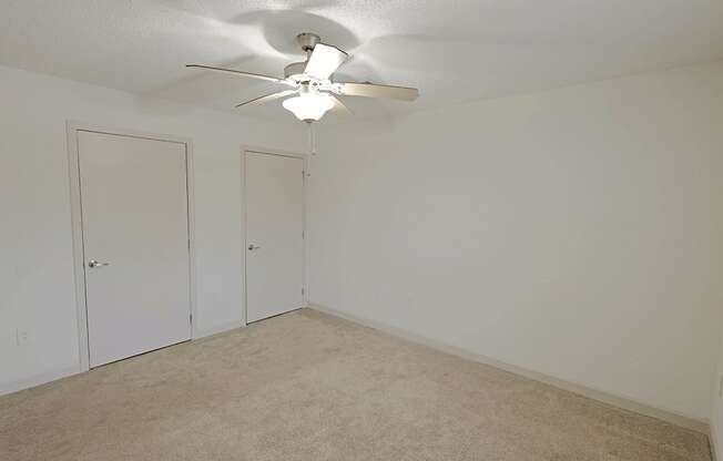 A room with a ceiling fan and carpeted floor.