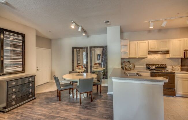 Furnished model Kitchen with black appliance package and dining nook with table and four chairs