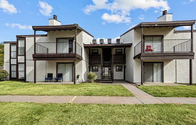 A two-story apartment building with a red car parked on the balcony.