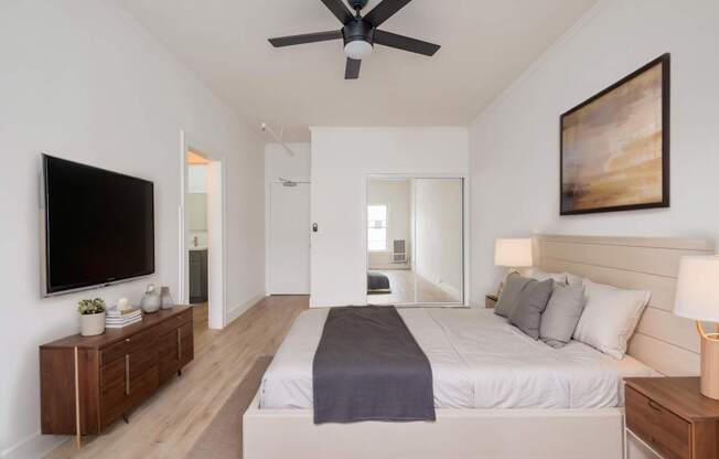 A bedroom with a bed, a ceiling fan, and a painting on the wall at Westmore Manor Apartments, Los Angeles, 90020