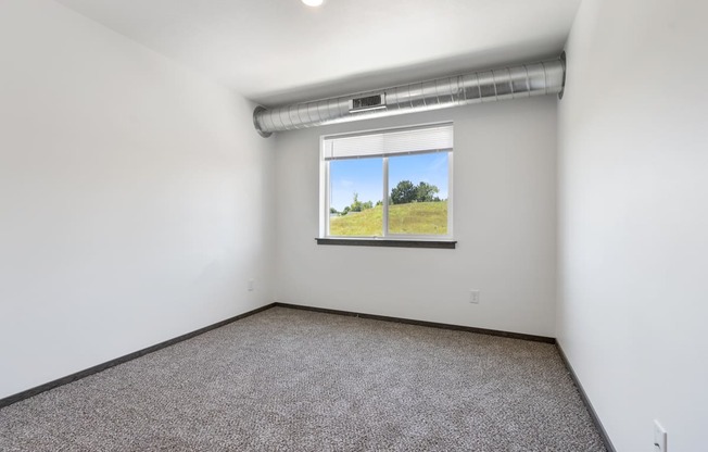 A room with a window showing a green field outside.
