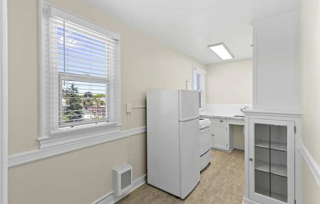 View of the kitchen with a refrigerator, white cabinets with glass pane, and a sink at Malloy Apartment Homes in Seattle, 98105