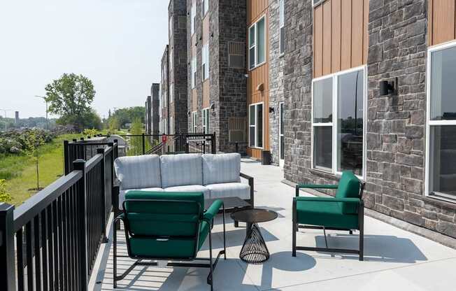A patio with a green chair and a white couch.