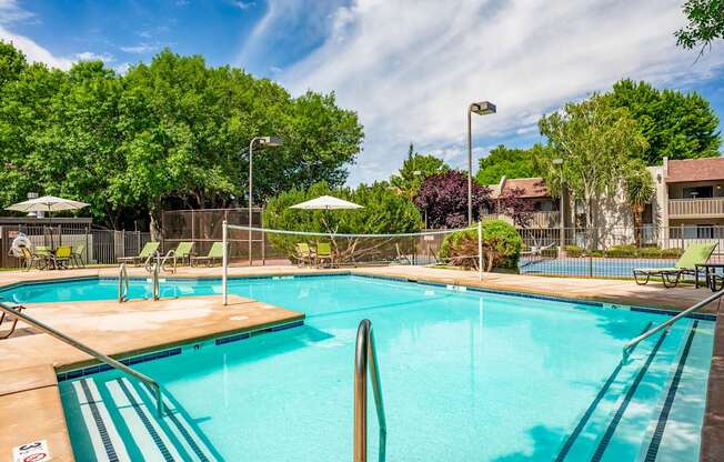 A large swimming pool surrounded by trees and lounge chairs.