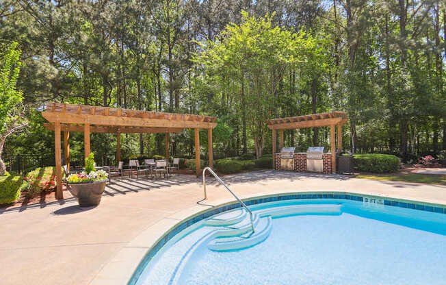 A pool with a slide and a pergola in the background.