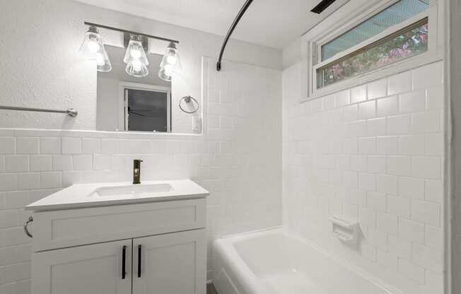 a white bathroom with a sink and a bath tub