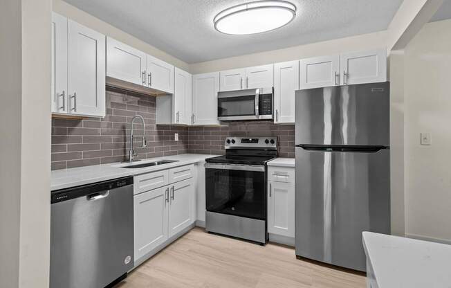 A kitchen with stainless steel appliances and white cabinets.