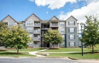 A large apartment complex with multiple balconies and trees in front.