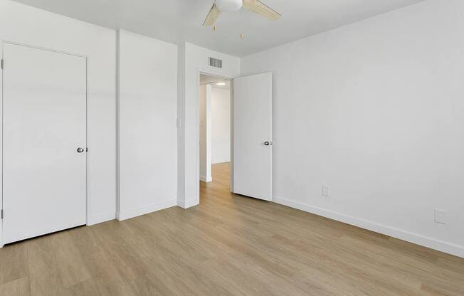 A room with a ceiling fan and white walls.
