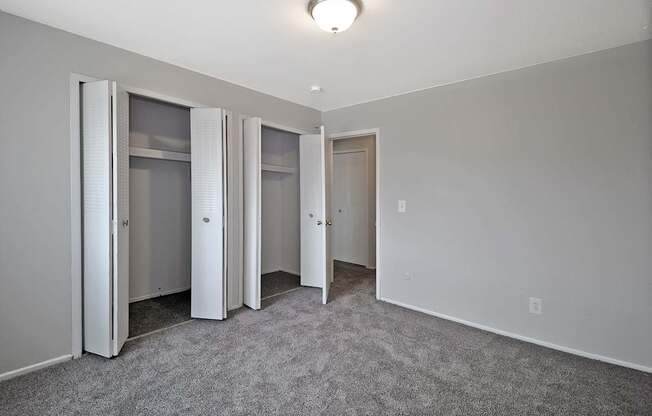 Bright bedroom with large closet, neutral paint, and soft carpeting at Warren Woods Apartments in Warren, MI.