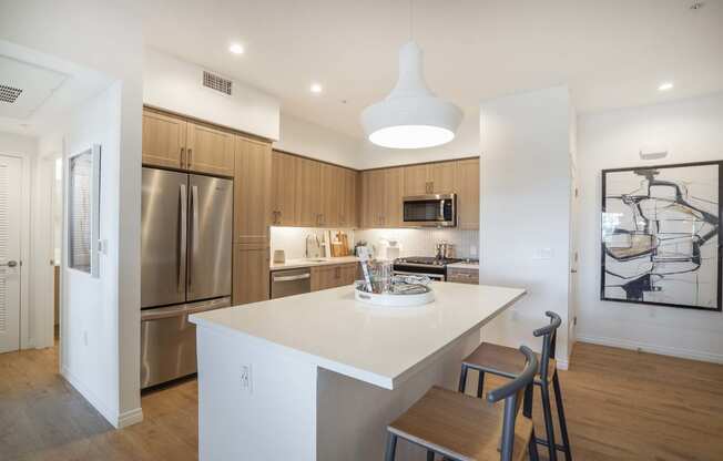 a kitchen with a large island and a stainless steel refrigerator