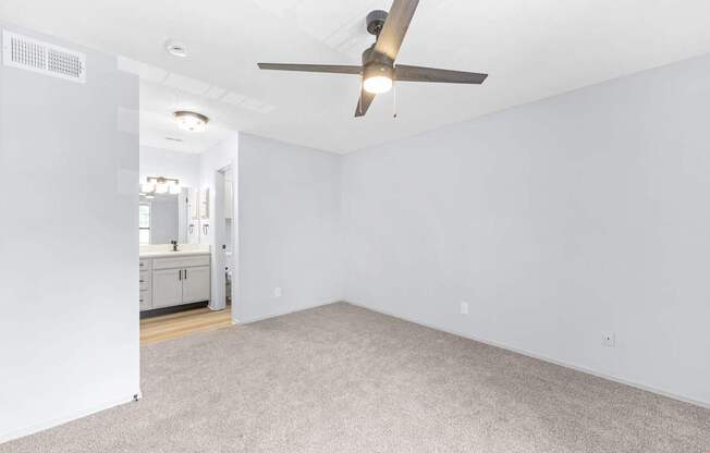 A room with a ceiling fan and carpeted floor.