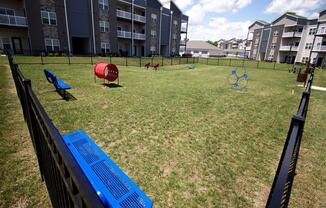 a dog park with agility equipment in front of an apartment building