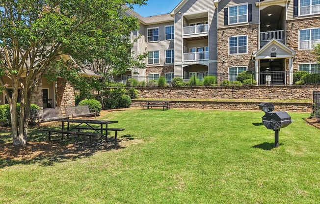 A large grassy area with grills, picnic tables, and benches