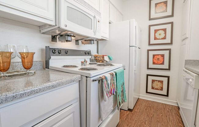 Furnished model apartment kitchen with a stove top oven and a microwave above it at Magnolia Apartments in Shreveport, LA