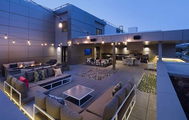 A modern outdoor seating area with a glass table and comfortable couches.