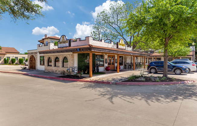 the front of a restaurant with a parking lot and trees