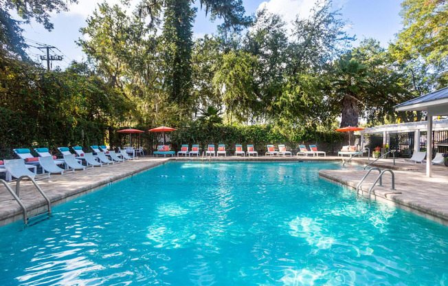 A large swimming pool surrounded by trees and lounge chairs.