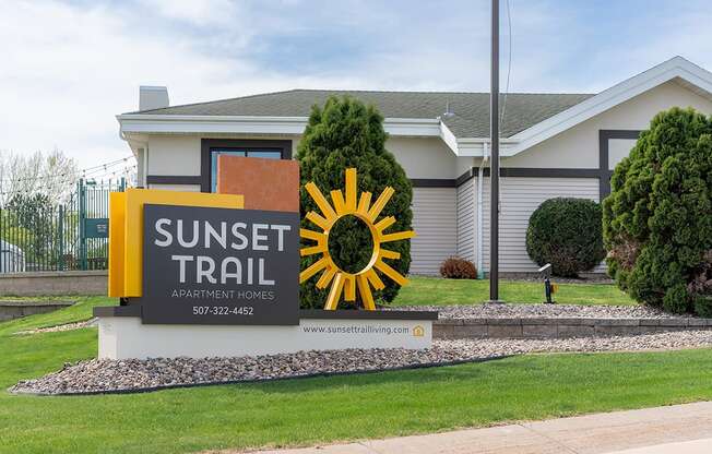 A sign for Sunset Trail Apartment Homes is displayed in front of a building.