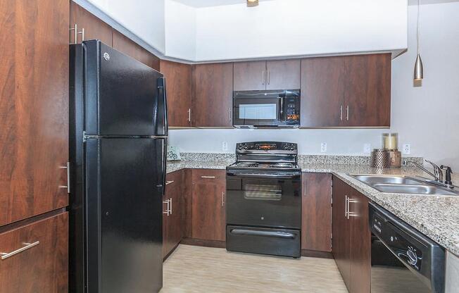 Large kitchen with black appliances and granite counter tops.