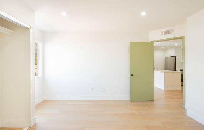 a living room with white walls and a green door