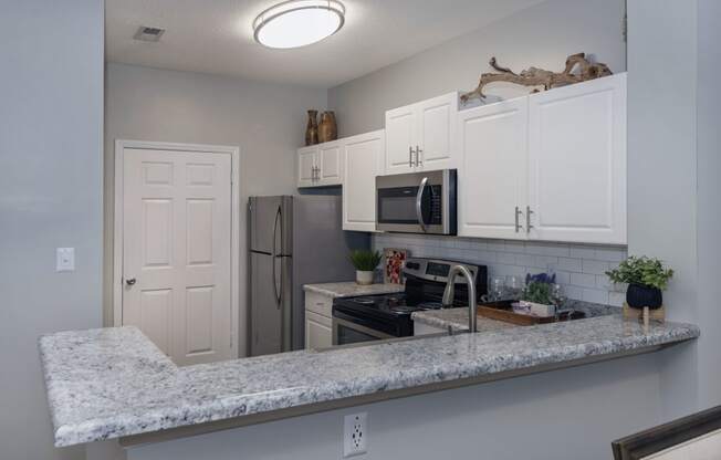 a kitchen with white cabinets and a granite counter top at Whitehall Estate apartments in Charlotte NC