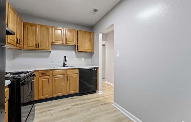 an empty kitchen with wooden cabinets and a black appliances