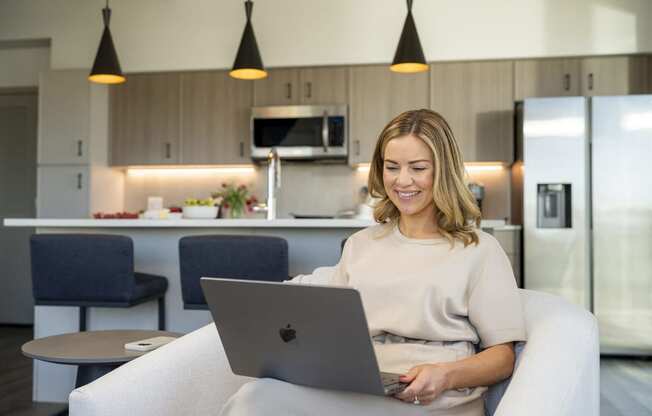 a woman sitting on a couch using a laptop computer at AVE Phoenix Sky, Phoenix, Arizona
