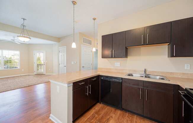 an empty kitchen with wooden floors and black cabinets