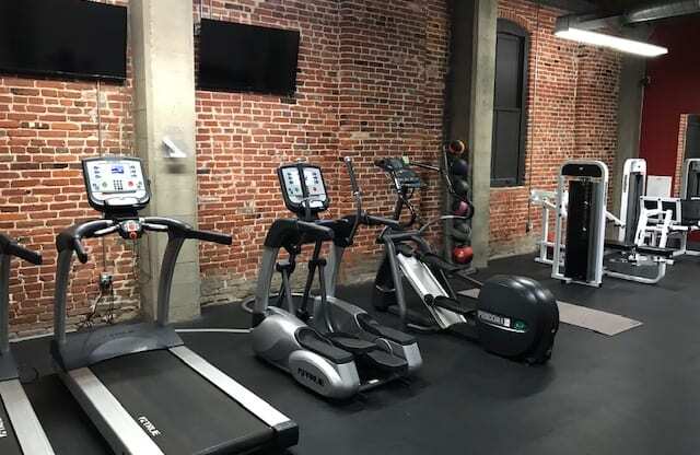 a group of exercise equipment in a gym with a brick wall