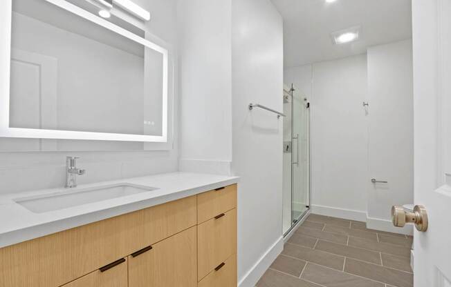 A bathroom with a sink, mirror, and shower.
