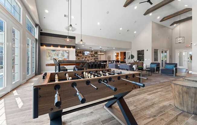 A foosball table is in the middle of a room with a bar and a fireplace.